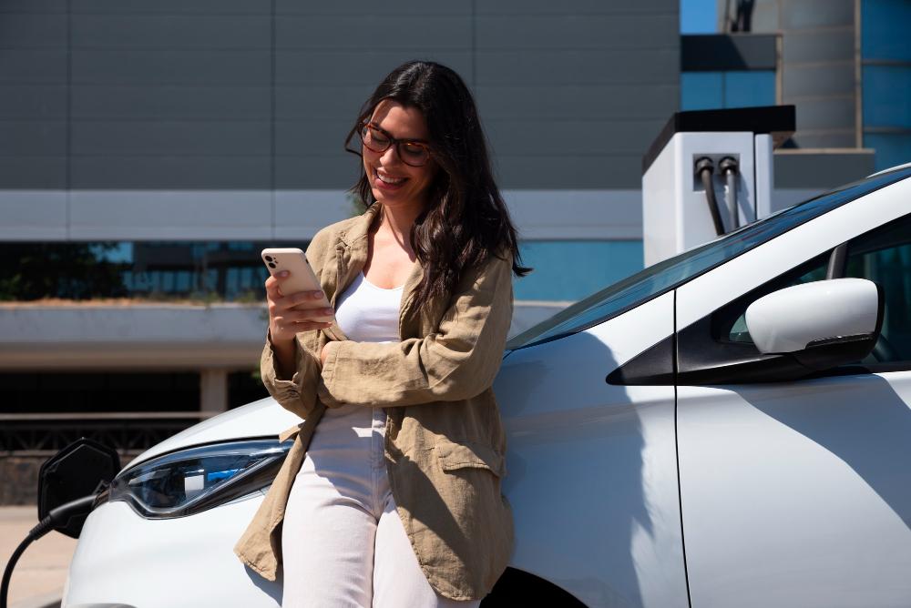 femme devant une voiture blanche qui recharge à l'électrique